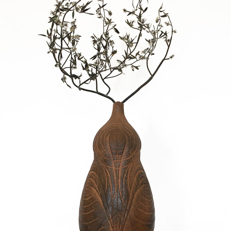 Unusually shaped ceramic pot with wintry metal leaves and flowers
